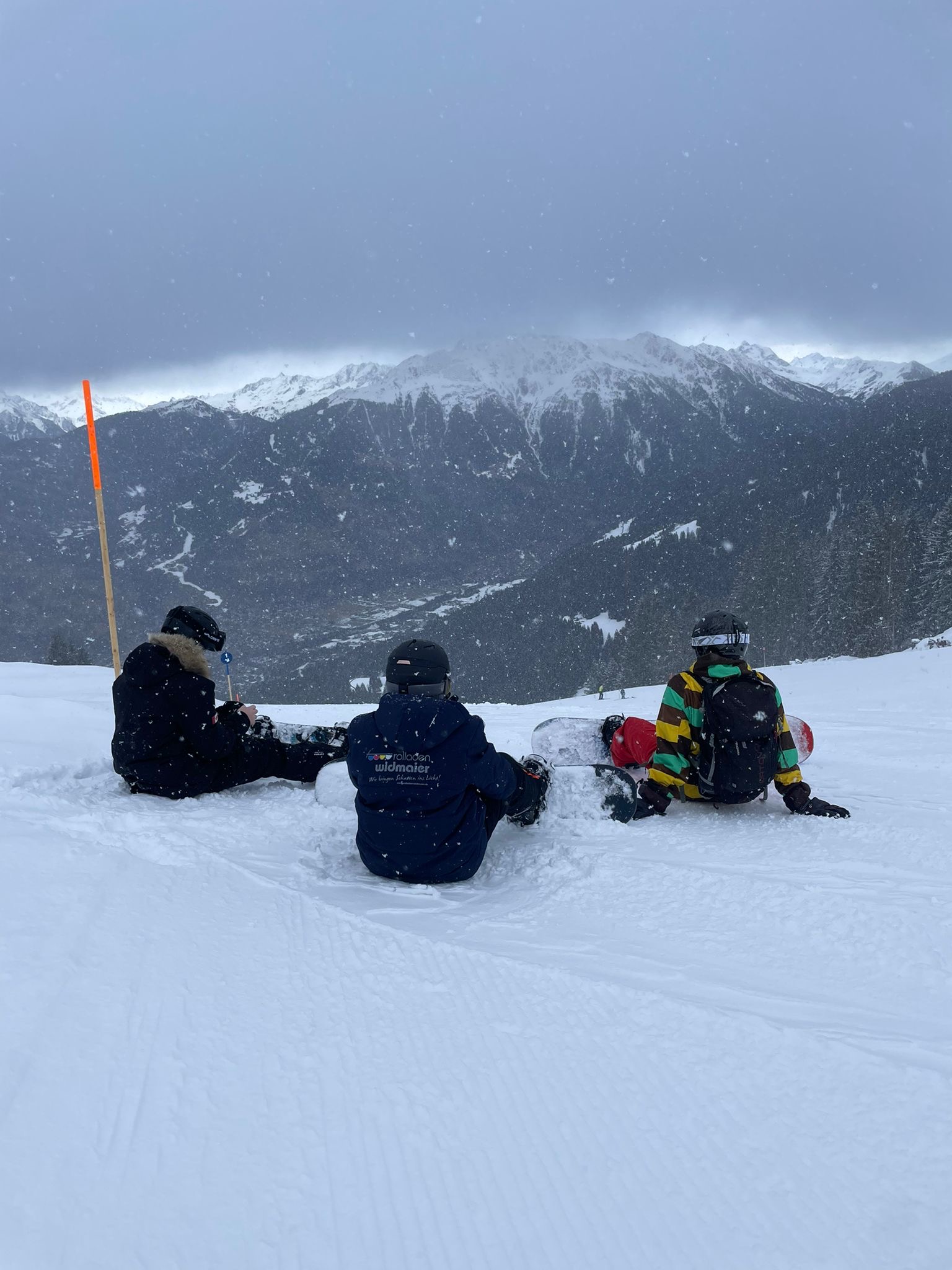 Drei Snowboarder auf einer Schneekuppe 