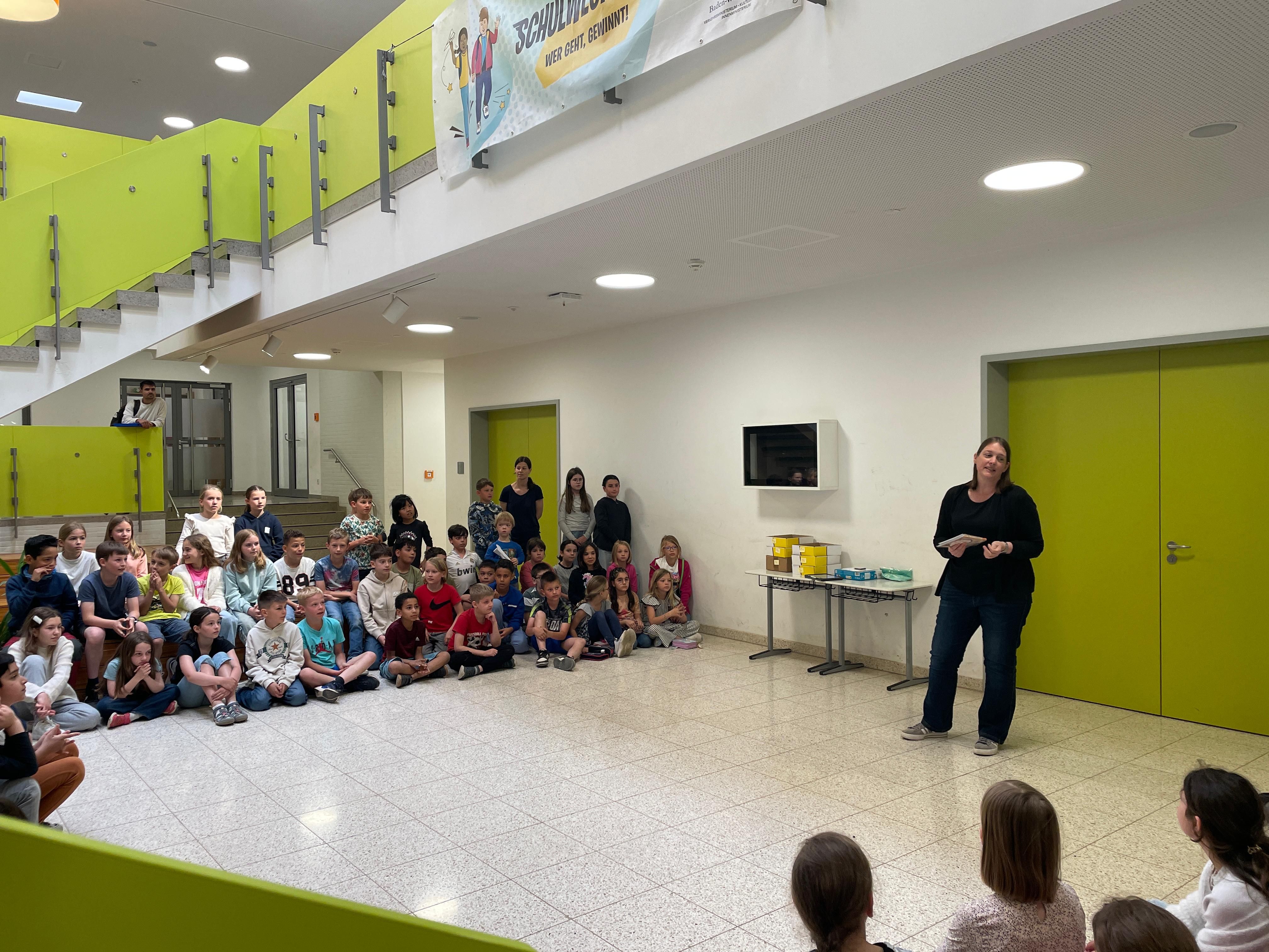 Eine Lehrerin steht vor den Schülern und  führt durch die Siegerehrung.