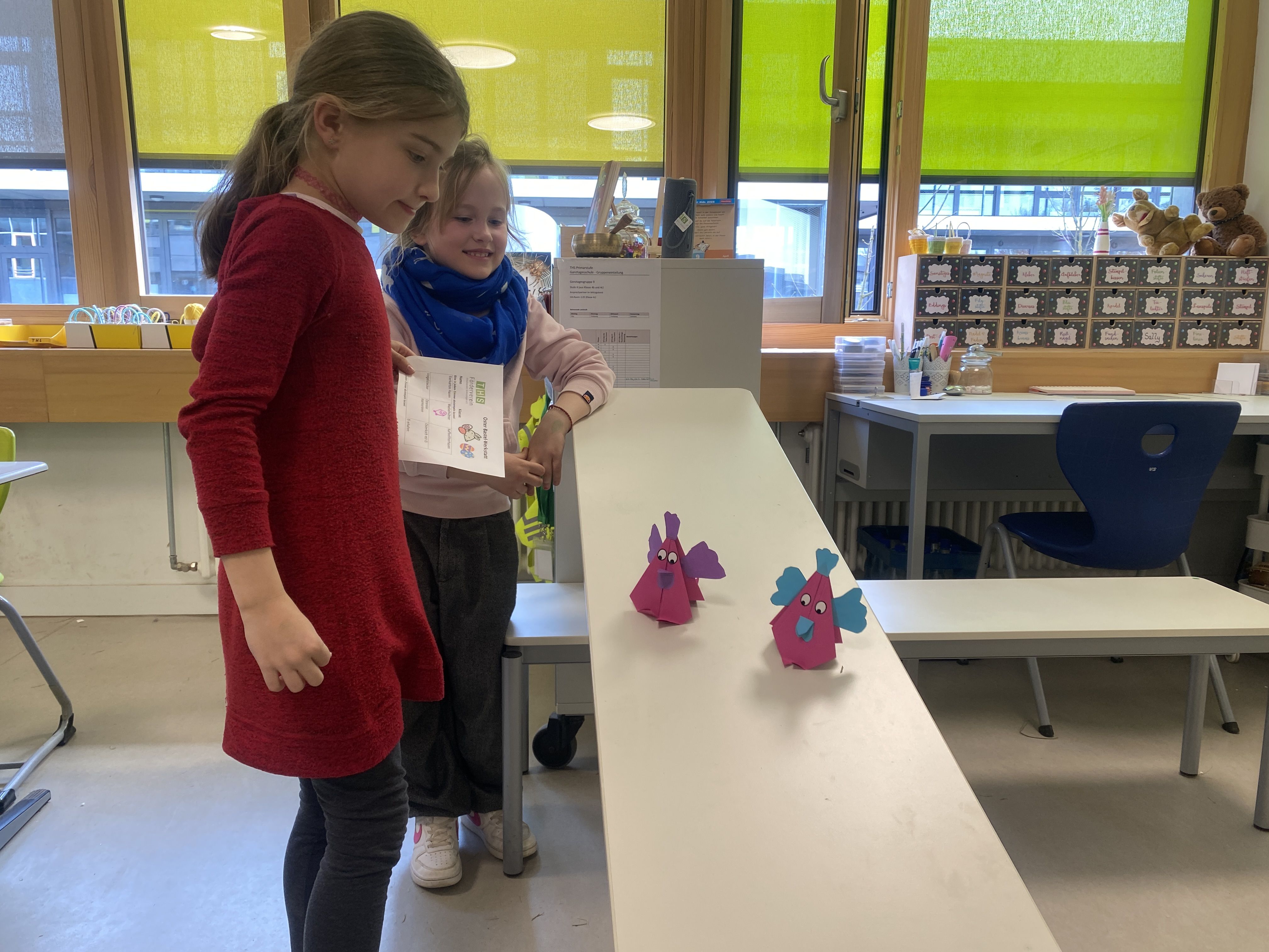 Zwei Kinder testen gebastelte Hühner auf einer Rampe.