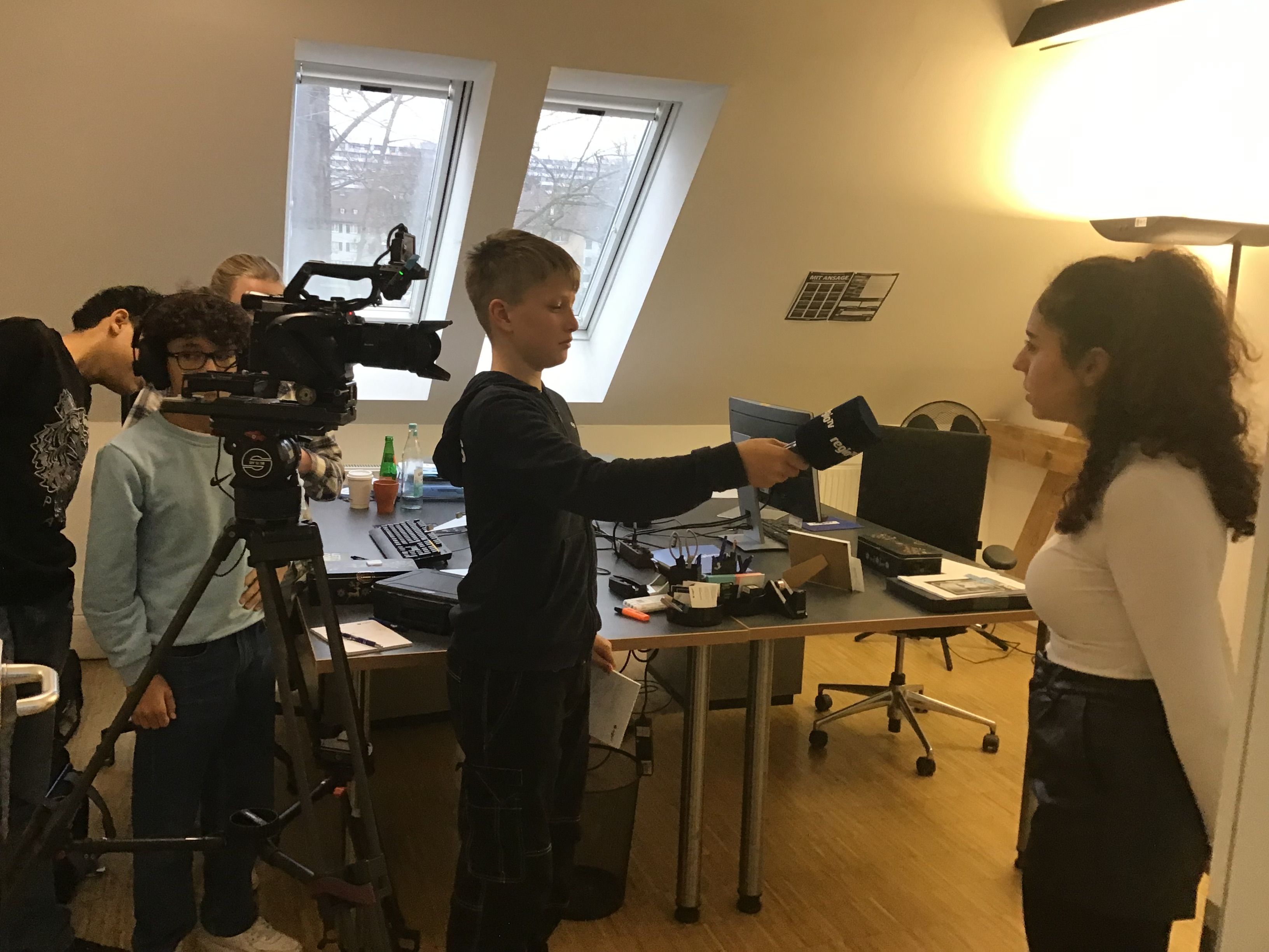 Schüler interviewen eine Reporterin. Im Bild eine Kamera.