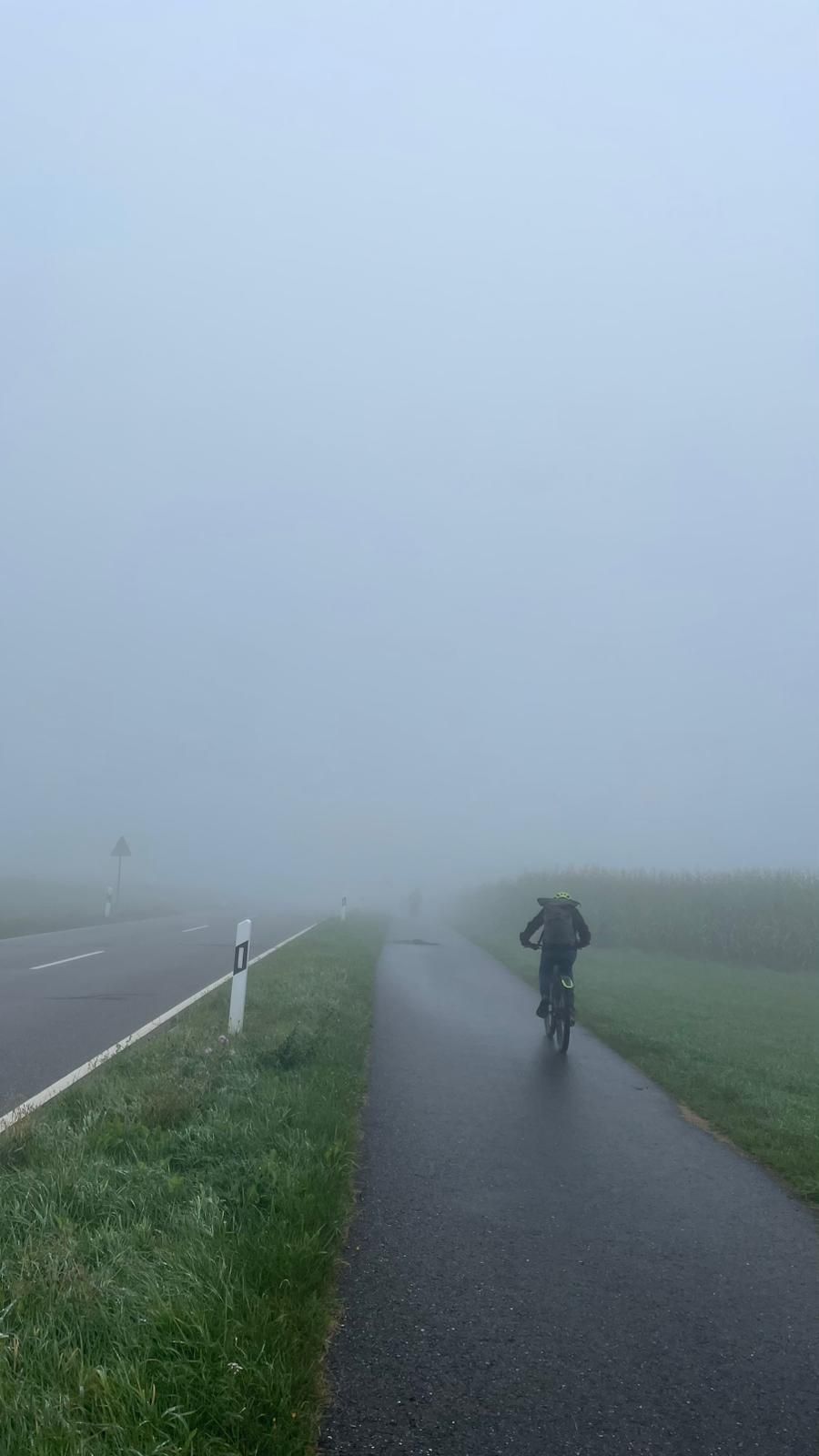 Ein Schüler fährt Fahrrad im Sprühregen