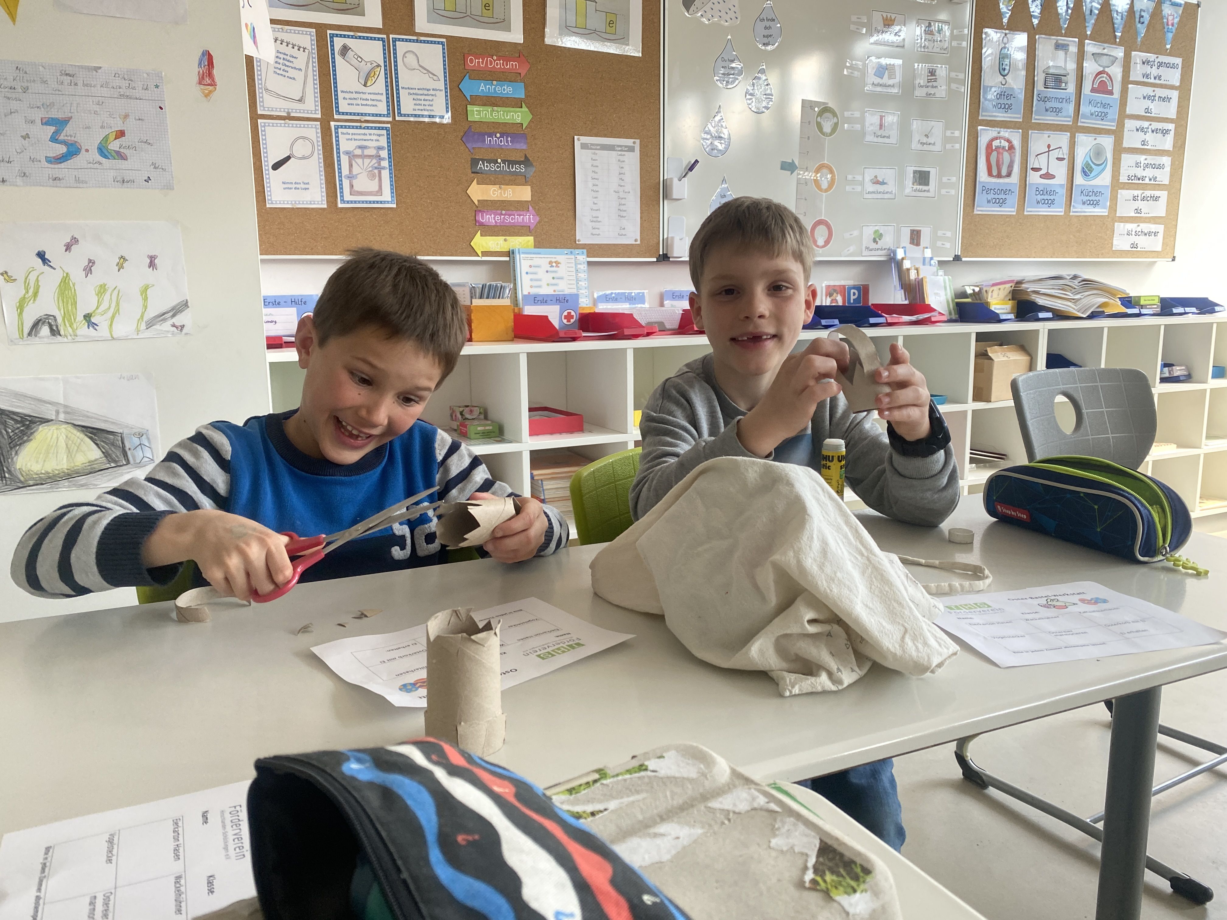 Zwei Jungen schneiden Klopapierrollen zurecht.